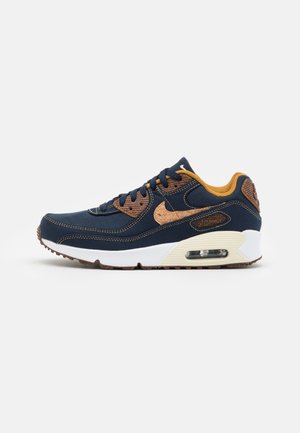 Granatowe sneakersy z brązowymi akcentami, białą podeszwą, widoczną poduszką powietrzną i ciemnobrązowymi sznurowadłami, pokazane z boku na białym tle.