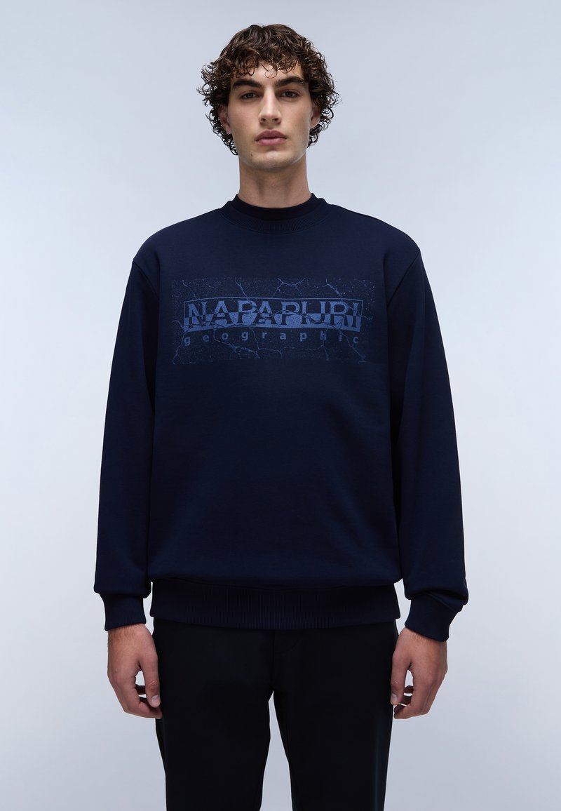 Sweatshirt bleu marine avec un imprimé graphique texturé affichant "NAPAPIJRI geographic" sur le devant. Manches et ourlet côtelés. Coupe décontractée.