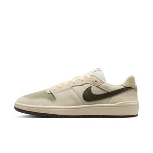 Beżowy, niskoprofilowy sneaker z jasnobrązowym logo Nike, zamszowymi i siateczkowymi dodatkami, kremowymi sznurowadłami i płaską gumową podeszwą.