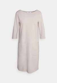 Beige knälång klänning gjord av mjukt tyg med rund halsringning, trekvartslånga ärmar och två stora framfickor.