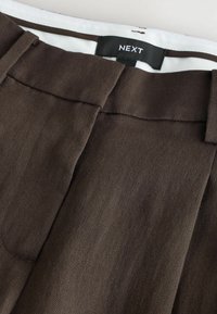 Braune, maßgeschneiderte Hose mit Gürtelschlaufen, vorderer Bundfalte und schwarzem NEXT-Logo auf dem weißen Innenbund.