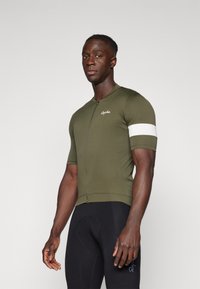 Tricou de ciclism cu mânecă scurtă, de culoare verde măslin, având un fermoar frontal și o dunga albă pe mânecă; realizat dintr-un material elastic.