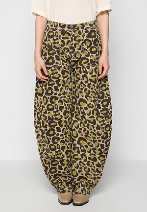Hose mit weitem Bein in braunem, grünem und beigem Leopardenmuster, getragen mit beigen quadratischen Schuhen und einem cremefarbenen kurzärmeligen Oberteil.