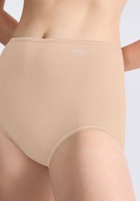 Beige trosor med hög midja i mjukt tyg, med en vit logotyp, sömlös design och sydda kanter.