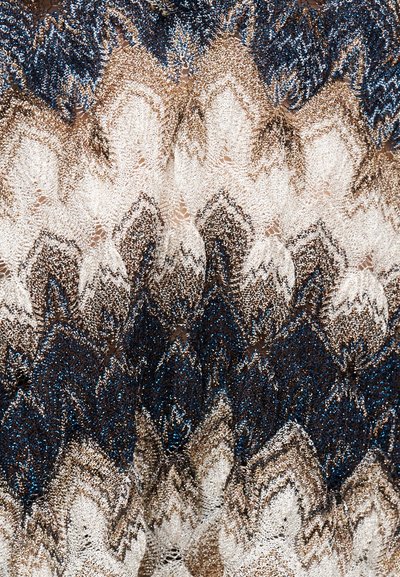 Κοντινή λήψη χρωματιστού πλεκτού υφάσματος με ζιγκ-ζαγκ μοτίβα σε ναυτικό μπλε, λευκό, καφέ και μπεζ αποχρώσεις.