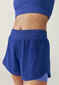 Pantaloni corti sportivi blu realizzati in tessuto leggero, dotati di una cintura elastica, tasche laterali e un orlo leggermente ventilato per una maggiore mobilità.