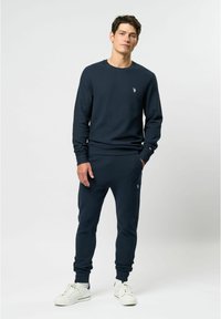 Marineblauwe sweatshirt en bijpassende joggingbroek van textiel met structuur, voorzien van een klein logo op de borst en zijstrepen op de broek.