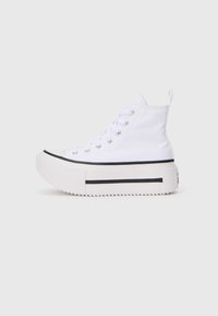Sneaker alte bianche con tomaia in tela, dotate di una spessa suola piattaforma bianca e strisce nere lungo il bordo inferiore.
