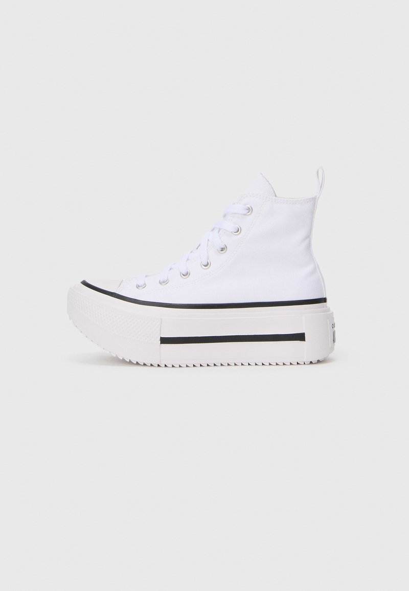 Sneaker alte bianche con tomaia in tela, dotate di una spessa suola piattaforma bianca e strisce nere lungo il bordo inferiore.