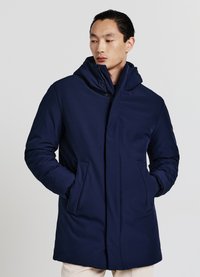 Cappotto imbottito blu navy con collo alto e cappuccio attaccato. Presenta tasche anteriori e un design elegante e minimalista. Texture liscia.