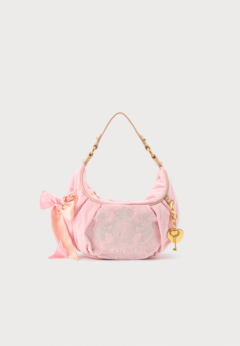Ružová zamatová kabelka cez rameno Juicy Couture so zlatým retiazkovým remienkom, príveskom v tvare srdca, vyšívaným logom a ružovou saténovou mašľou.