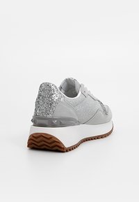 Baskets grises avec talon pailleté argenté, semelle plateforme blanche, semelle extérieure marron texturée et accents gris à motifs, vues de l'arrière gauche.