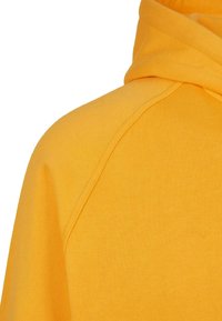 Sudadera con capucha en un brillante color amarillo, con una textura de algodón suave, mangas ranglán y un ajuste relajado y cómodo.
