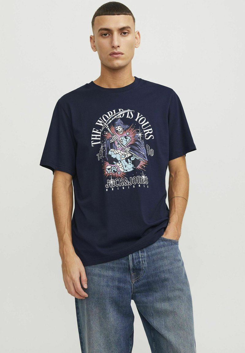 T-shirt en coton bleu marine avec un design graphique portant le texte "LE MONDE EST À VOUS" et une figure stylisée. Manches courtes, coupe décontractée.