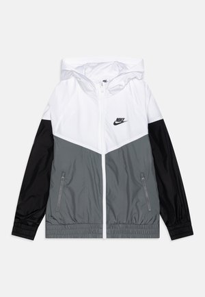 Nike vindjakke med hvid og grå farveblokdesign og sorte accenter, med lynlåslommer og justerbar hætte.