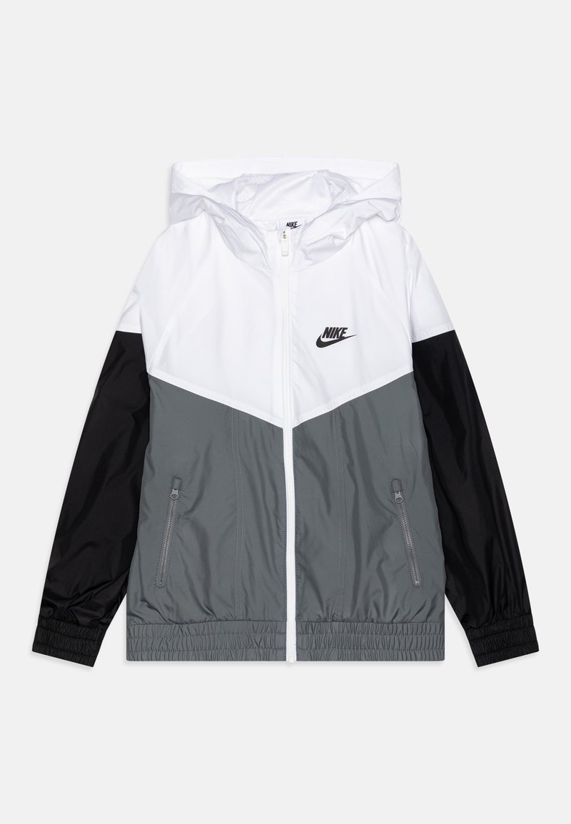 Nike větrovka s bílým a šedým blokovým designem a černými akcenty, s uzavíratelnými kapsami na zip a nastavitelnou kapucí.