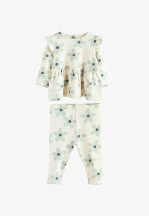 Gėlių rašto vaikų apranga, susidedanti iš ilgomis rankovėmis marškinėlių su raukiniais ir sudarančių kojinių, abi šviesių spalvų ir minkštos medžiagos.