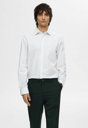 White striped button-up shirt with blue stripes, long sleeves, worn with dark green trousers. Smooth fabric and fitted design.
