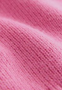 Tessuto lavorato a maglia rosa con una texture morbida, che presenta un modello uniforme di punti e una leggera peluria.