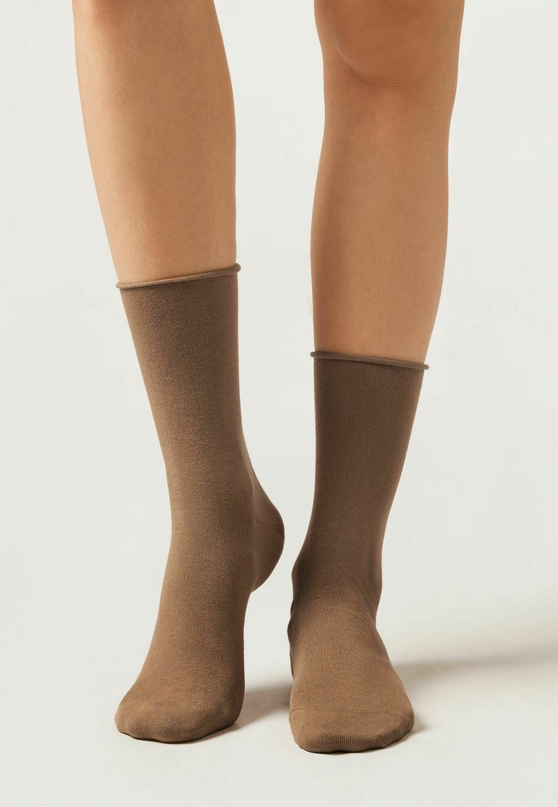Braune Socken mit glatter Oberfläche, mittellang bis zur Wade und elastischem Bund. Weiches Material in einfarbiger Optik ohne sichtbare Muster oder Hardware.