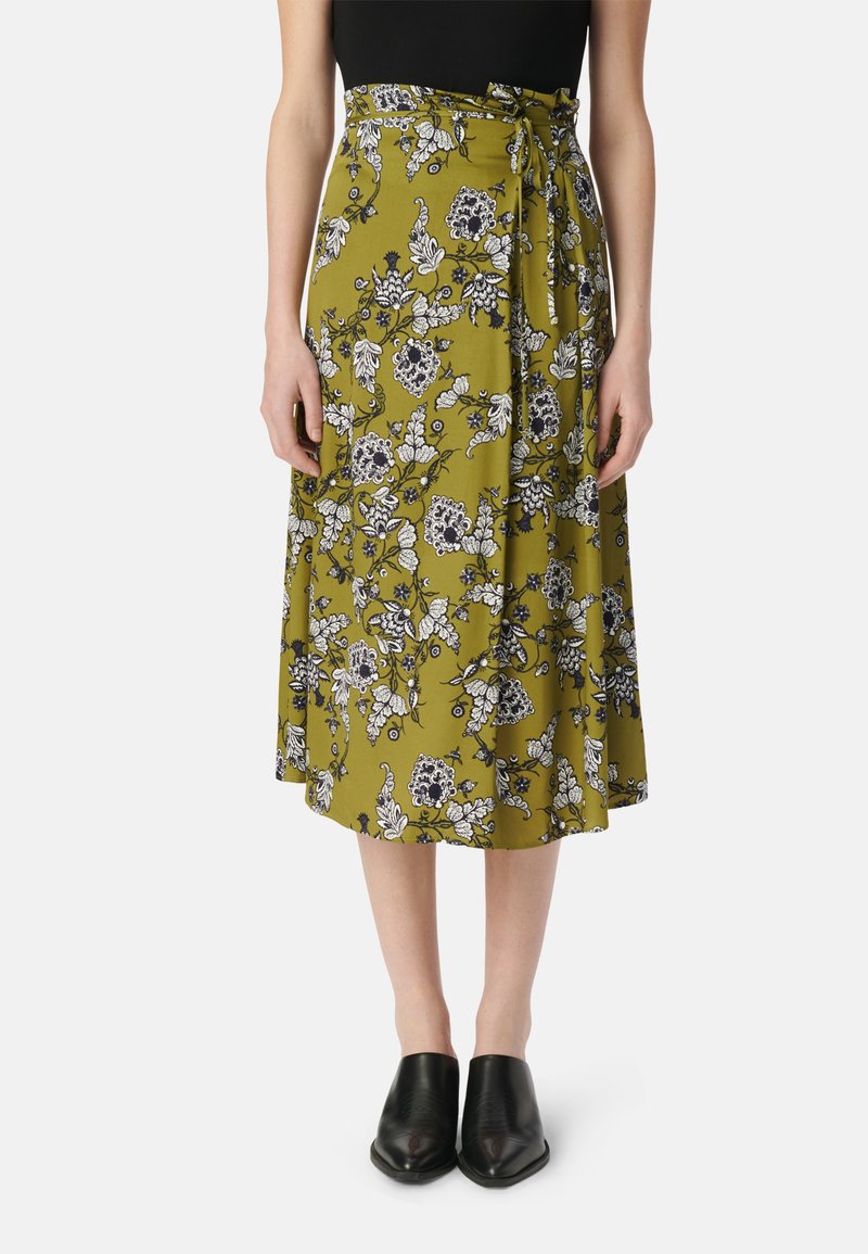 Olijfgroene bloemen midi-rok met zwart-witte patronen, voorzien van een strik taille en een vloeiende stijl. Gekocht met zwarte instapschoenen.