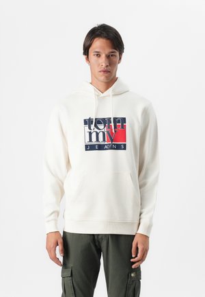 Grietinė megztinis su kengūros kišene, priekyje su navy, raudona ir balta grafika "tommy JEANS" logotipu. Minkšta medžiaga, reguliuojama raišteliais.