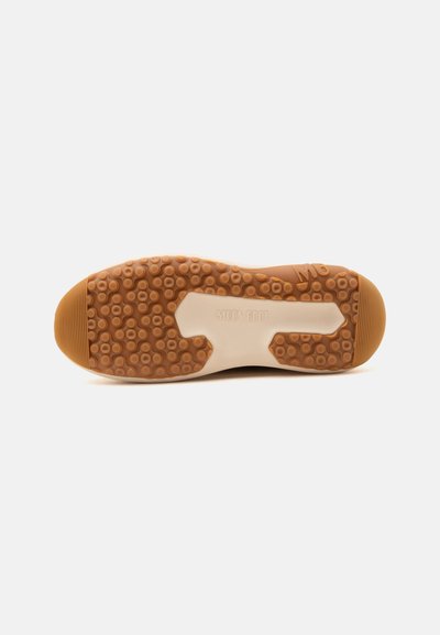 Semelle d'une chaussure en caoutchouc marron avec un motif texturé et "MOON BOOT" embossé au centre sur fond blanc.