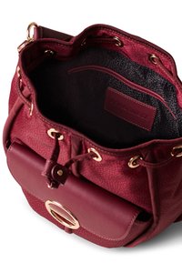 Zaino bordeaux con materiale sintetico testurizzato, dettagli in metallo dorato, chiusura con cordoncino e tasca frontale con bottone a pressione circolare.