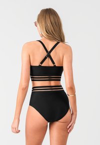 Black two-piece swimsuit featuring a bandeau top with cross-back straps and sheer horizontal panels at the waist and legs. Smooth texture.
