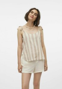 Beige en witte gestreepte tanktop met schouderbandjes, met een gebogen zoom en een lichte stofstructuur. Gepaarde met crème-kleurige shorts.