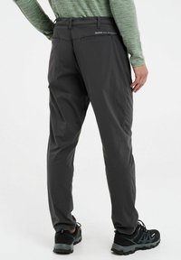 Grijze outdoor broek van lichtgewicht materiaal, met een rechte snit, standaard tailleband en zichtbaar logo op de achterkant.