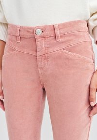 Lichtroze corduroy broek met een hoge taille, riemlussen, zilveren knoopsluiting en schuine zijzakken, met een geribbeld textuur.