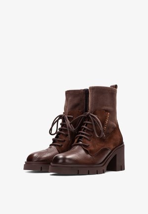Bruine enkelboots met een combinatie van glad leer en suede, vetersluiting aan de voorkant, zijrits en een chunky hoge hak.