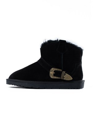 Black suede ankle boot with a textured surface, featuring a decorative gold buckle and soft fur lining at the top. Low rubber sole.