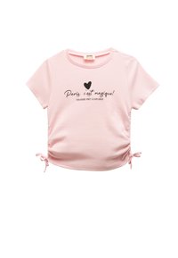 Camisa corta de manga corta color rosa claro con los laterales fruncidos, que presenta una impresión gráfica negra con el texto "¡París, es mágico!" y un corazón.