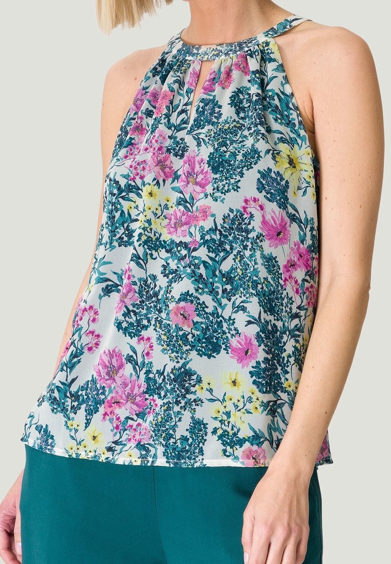 Blouse sans manches en tissu léger avec un col plissé, motif floral multicolore avec des accents rose, turquoise et jaune.