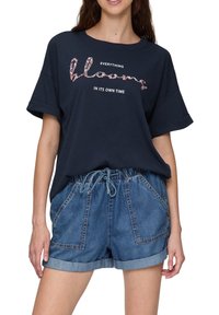 Navy blauwe katoenen T-shirt met korte mouwen en een bloemig tekstontwerp, gecombineerd met lichte denimshorts met opgerolde zomen en een trekkoord in de taille.