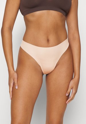 Perzikkleurige naadloze stringonderbroek met een gladde textuur en brede elastische tailleband, met minimale bedekking en een low-rise ontwerp.