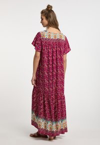 Maxi šaty v živé magentě s květinovým vzorem, vrstvenou sukní a kontrastním vzorovaným lemem. Krátké rukávy s volným střihem.