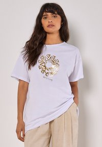 Weißes Baumwoll-T-Shirt mit Rundhalsausschnitt und kurzen Ärmeln, mit einem goldenen Sonnen-Motivdruck und dem Text "Always Sunny."