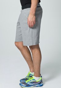 Šedé sportovní šortky z měkkého materiálu s přímým střihem. Kombinované s modrými a zelenými běžeckými botami s prvky z síťoviny.