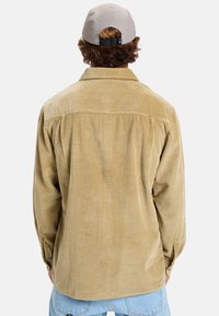 Lichtbruin corduroy overhemd met een spread collar, knoopmanchetten en een relaxed fit. Textuur oppervlak met subtiele verticale ribbels.
