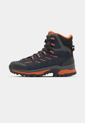 Hiking boot with a black and gray suede upper, orange accents, durable rubber sole, and metal eyelets for laces. Ankle-high design.