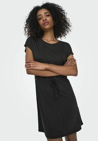 Robe noire à manches courtes avec une coupe décontractée, taille à cordon et tissu doux. Texture lisse, design jusqu'aux genoux et encolure arrondie.