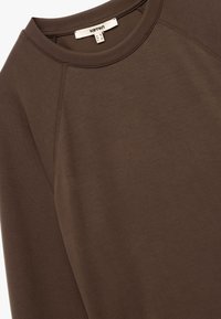 Bruine sweatshirt met een ronde hals en raglanmouwen. Zachte textuur met minimale stikdetails, met een label aan de binnenkant van de hals.