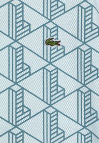 Patroonstof met een lichtblauwe geblokte achtergrond, met geometrische trapachtige ontwerpen in teal. Inclusief een groene krokodillologo.