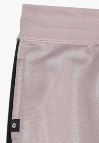 Jasnoróżowe legginsy sportowe z teksturowanym wykończeniem i czarnymi akcentami po bokach. Posiadają elastyczny pasek w talii oraz małą naszywkę z logo.