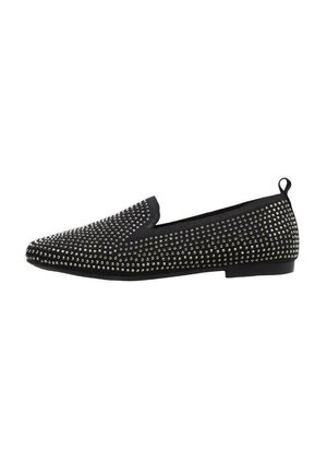 Zapato negro tipo slip-on decorado con tachuelas plateadas, que cuenta con una puntera redonda y una suela de goma plana; diseño sencillo sin cordones visibles.