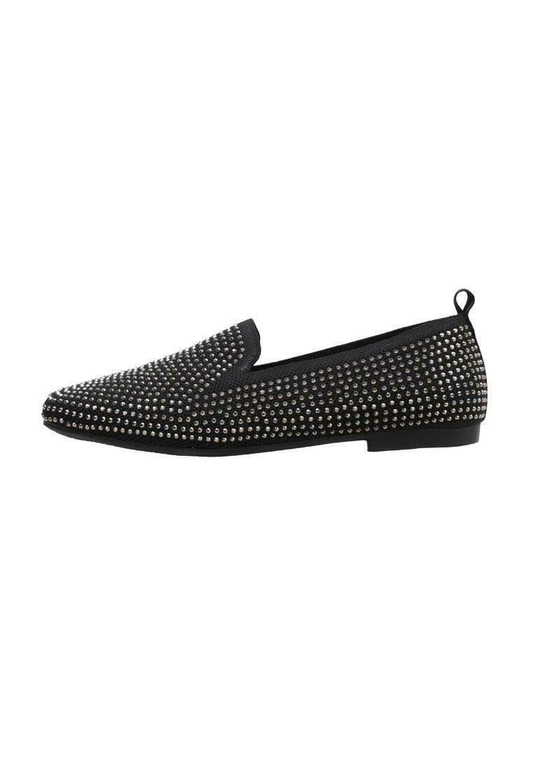 Zapato negro tipo slip-on decorado con tachuelas plateadas, que cuenta con una puntera redonda y una suela de goma plana; diseño sencillo sin cordones visibles.