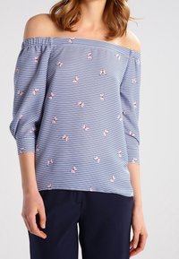 Tričkohra bez ramínek v modro-bílých pruzích, s malými růžovými květinovými vzory. Tříčtvrteční nabírané rukávy s vykrojenými švy na ramenech.